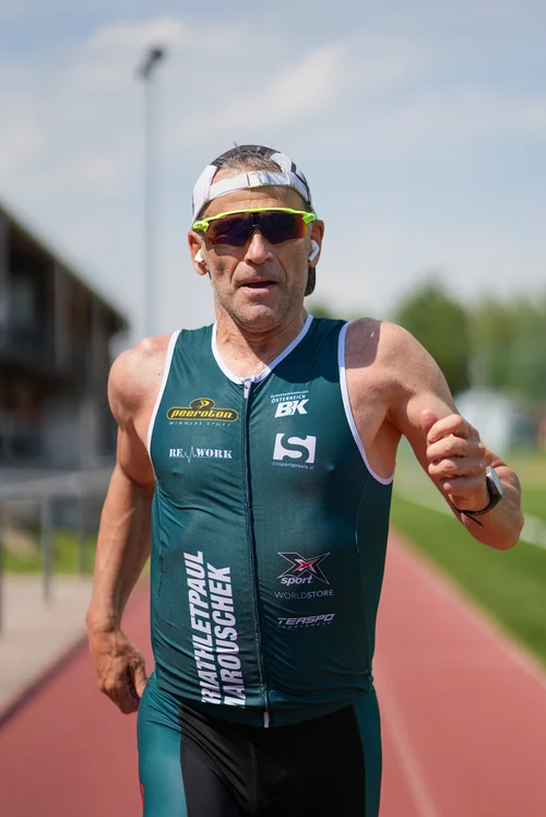 „Paul Marouschek läuft auf einer Laufbahn in seinem grünen Triathlon‑Einteiler“